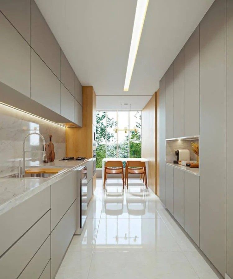 Cozinha paralela espaçosa com piso de pedra branco e marcenaria em tons neutros