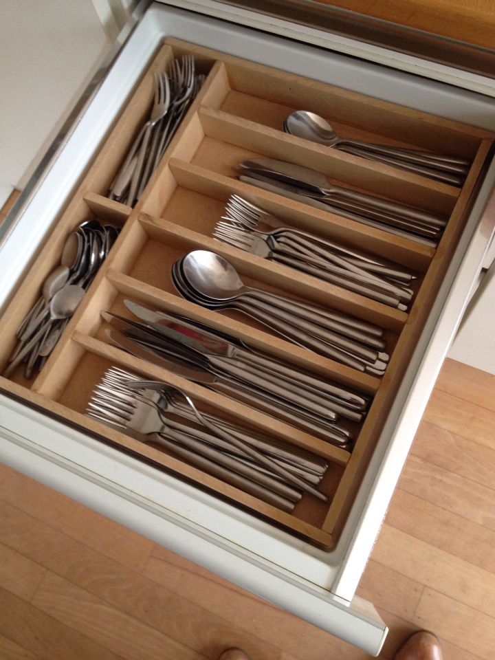 Divisor de talheres dentro de uma gaveta, com talheres dispostos de forma organizada por tipo em ...