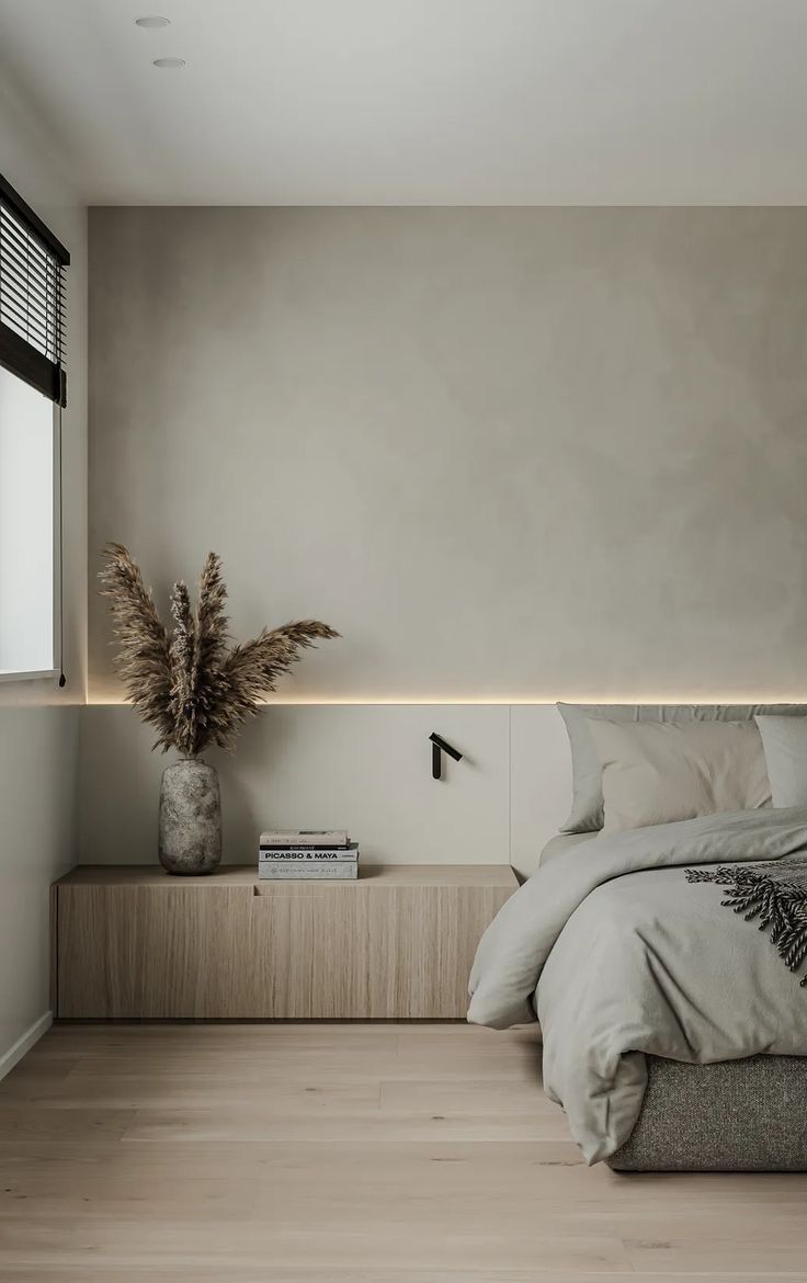 Dormitorio com parede cloud dancer, cama em cinza claro e mesa de cabeceira em madeira tom claro