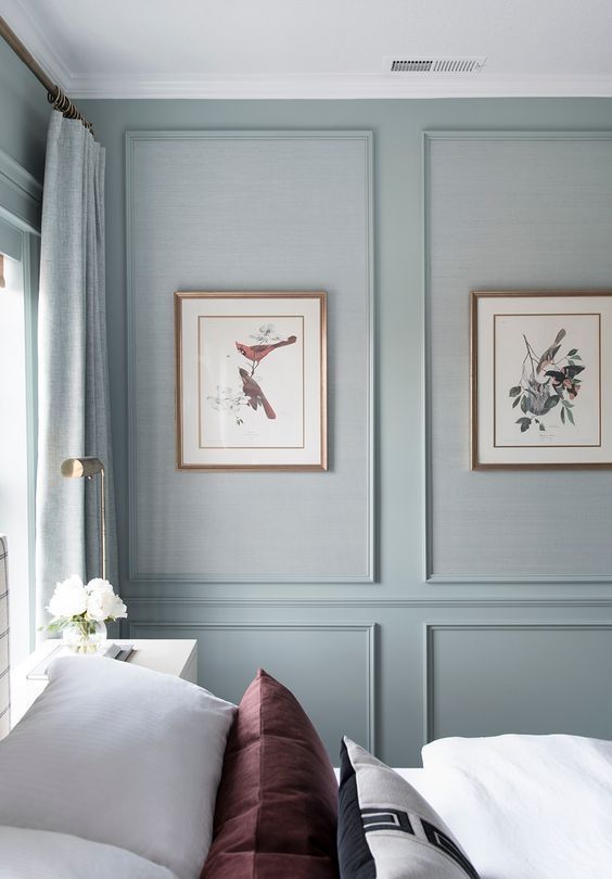 Dormitório com paredes boiserie com azul pastel com quadros centralizados
